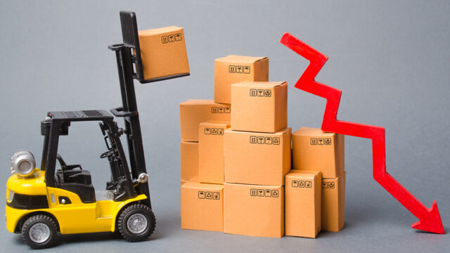 Minature forklift lifting carboard boxes with red graph arrow pointing downwards